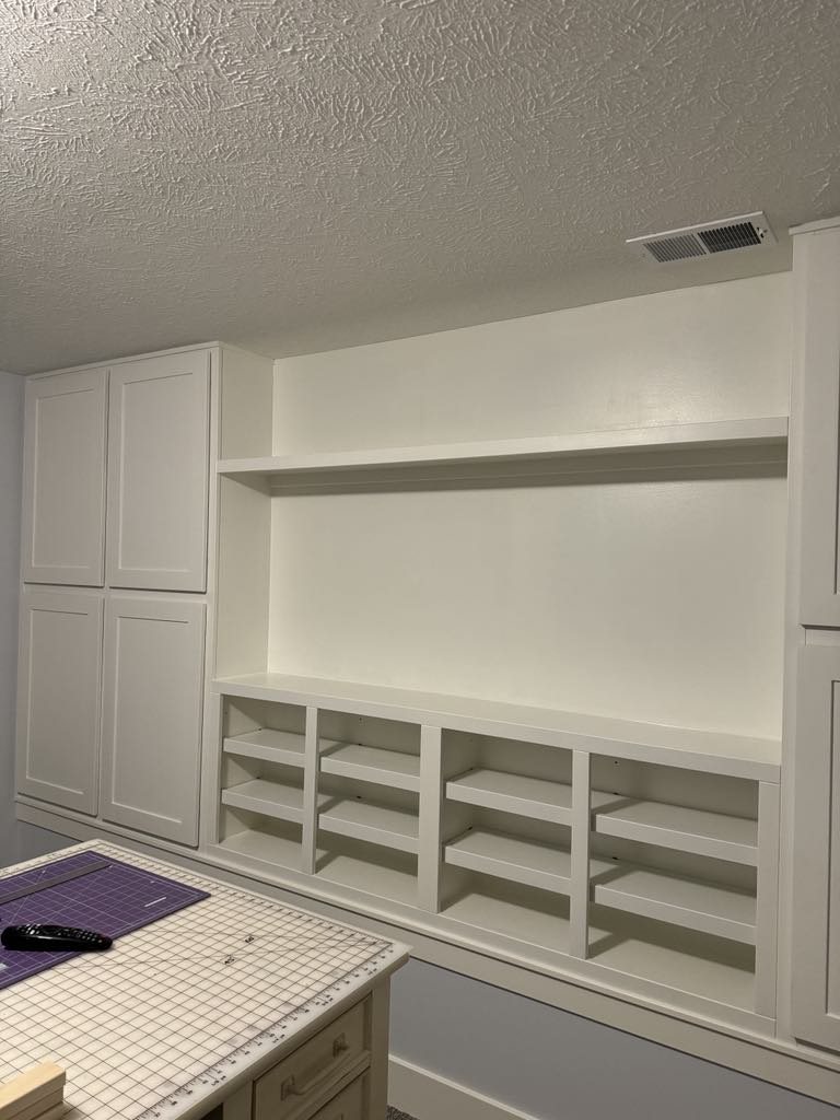 Craft room built-in work surface open shelves and tall cabinets