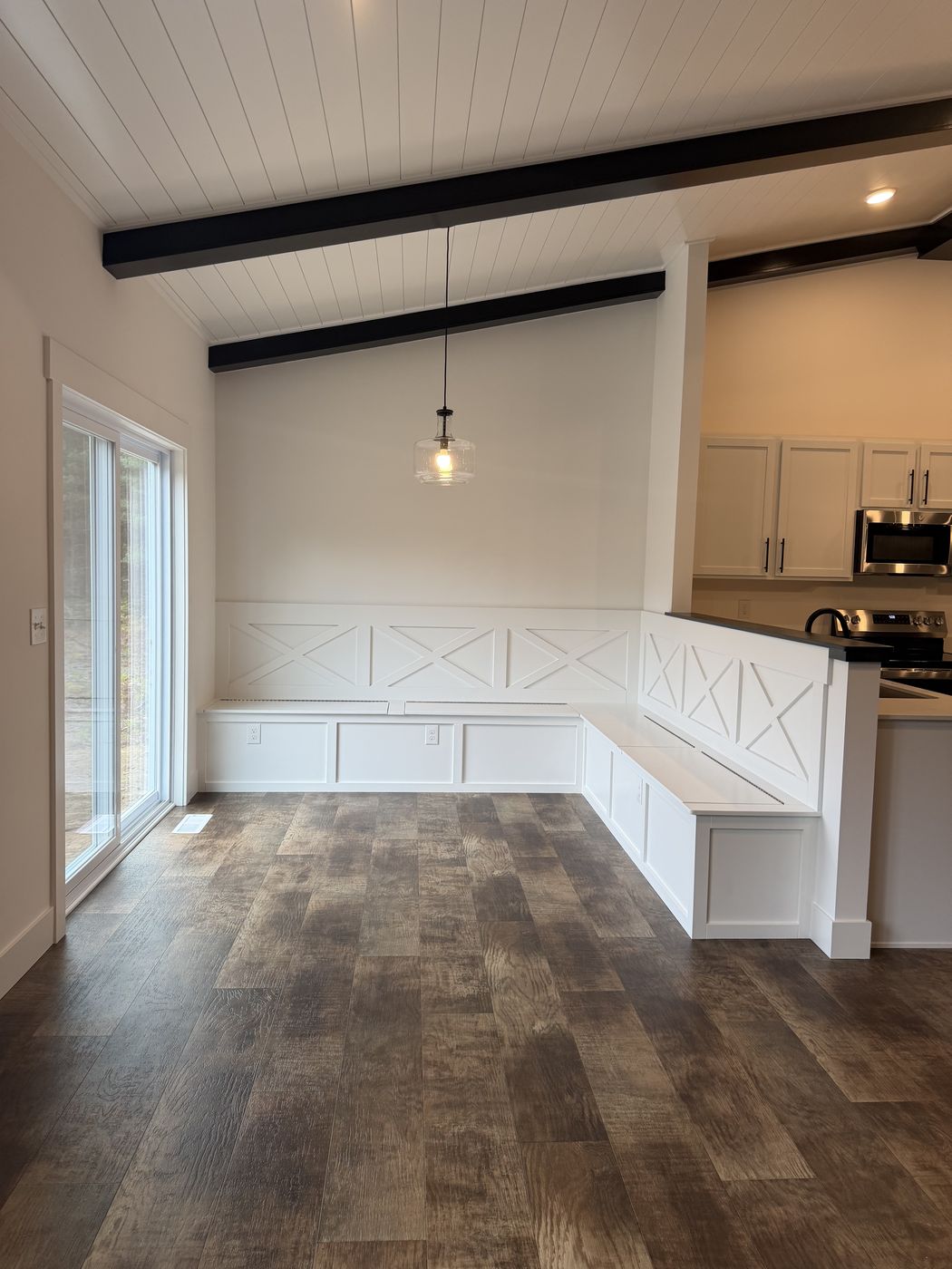 After: Finished white L-shaped kitchen banquette with X-panel detail and wood seat