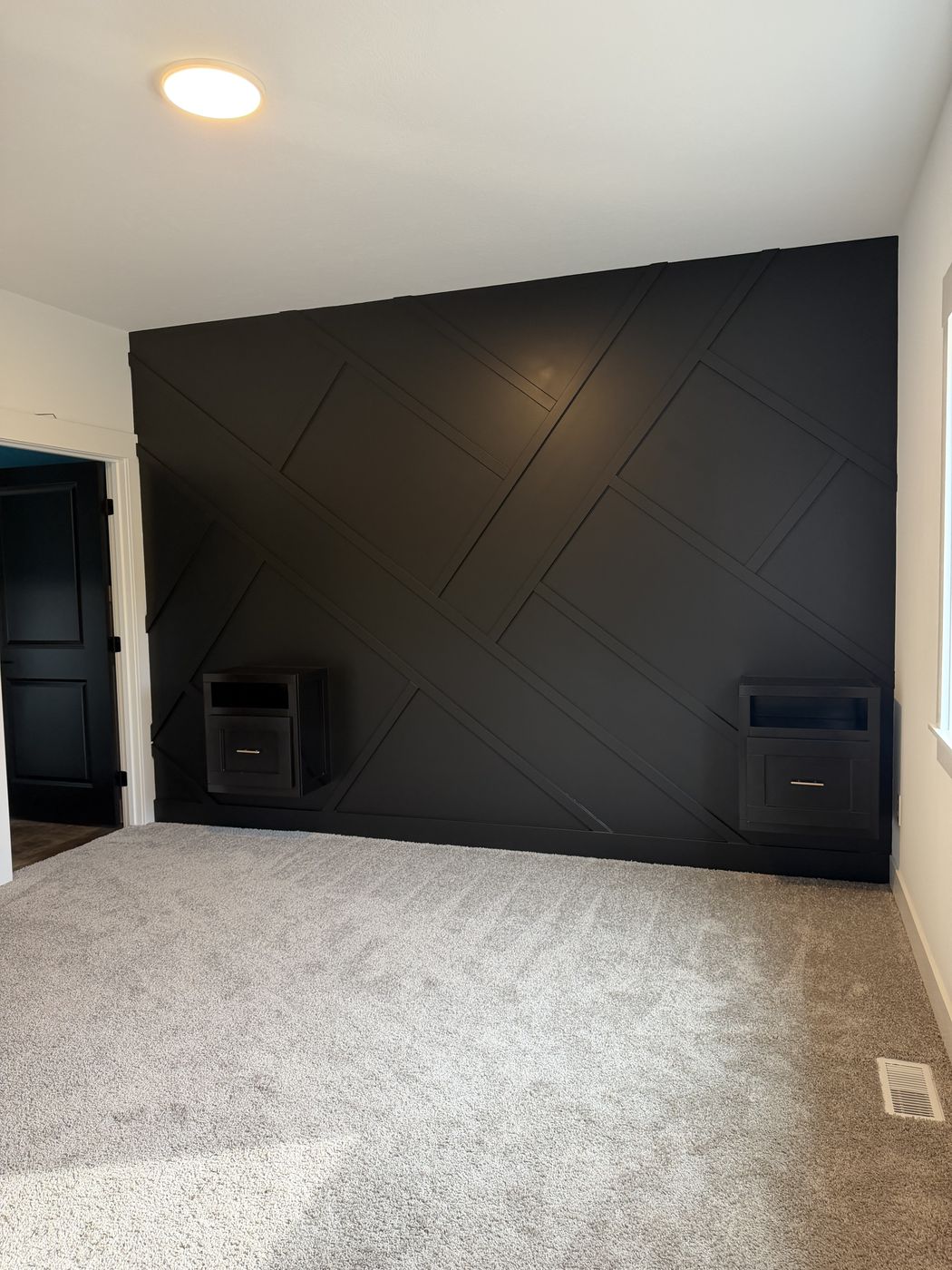 After: Finished black angled batten wall with two wall niches in a carpeted bedroom