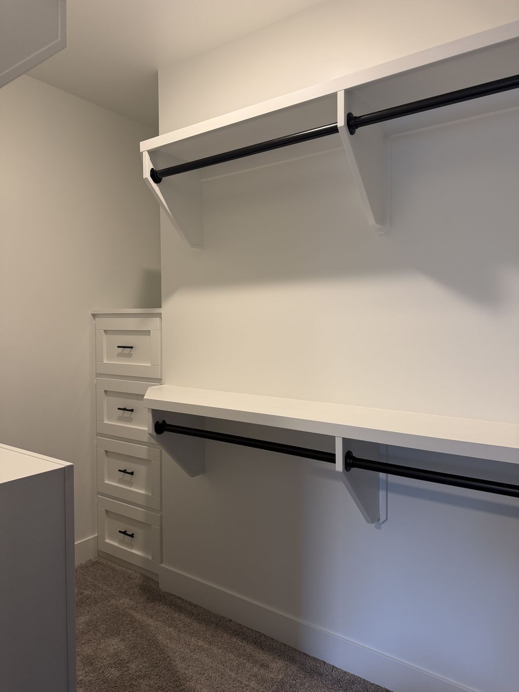 Closet with white shelving, double hanging rods, and a drawer bank