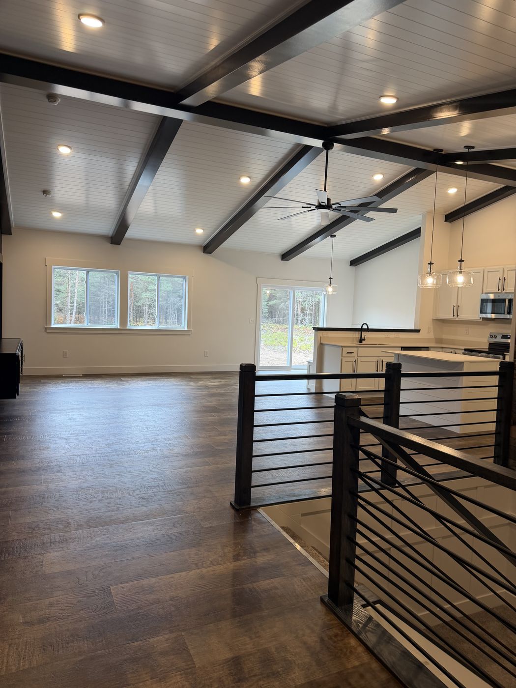 After: finished great room with black beamed ceiling and stair rail