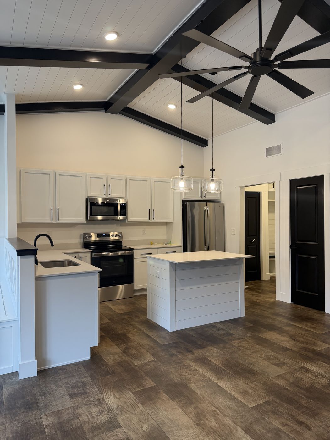 White kitchen with shiplap island, pendants, and black beams above