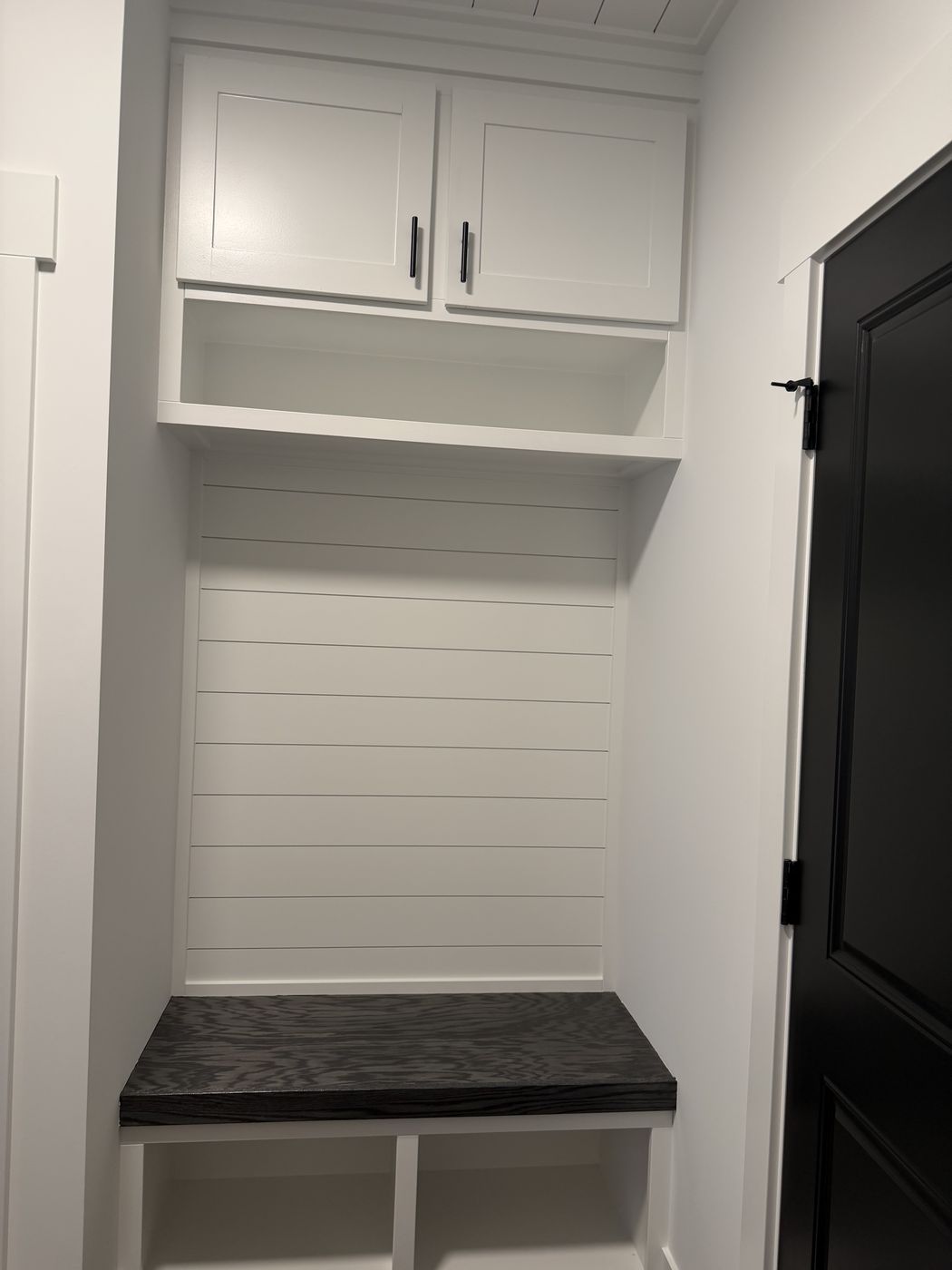 White mudroom locker with upper cabinets, shiplap back, and dark bench