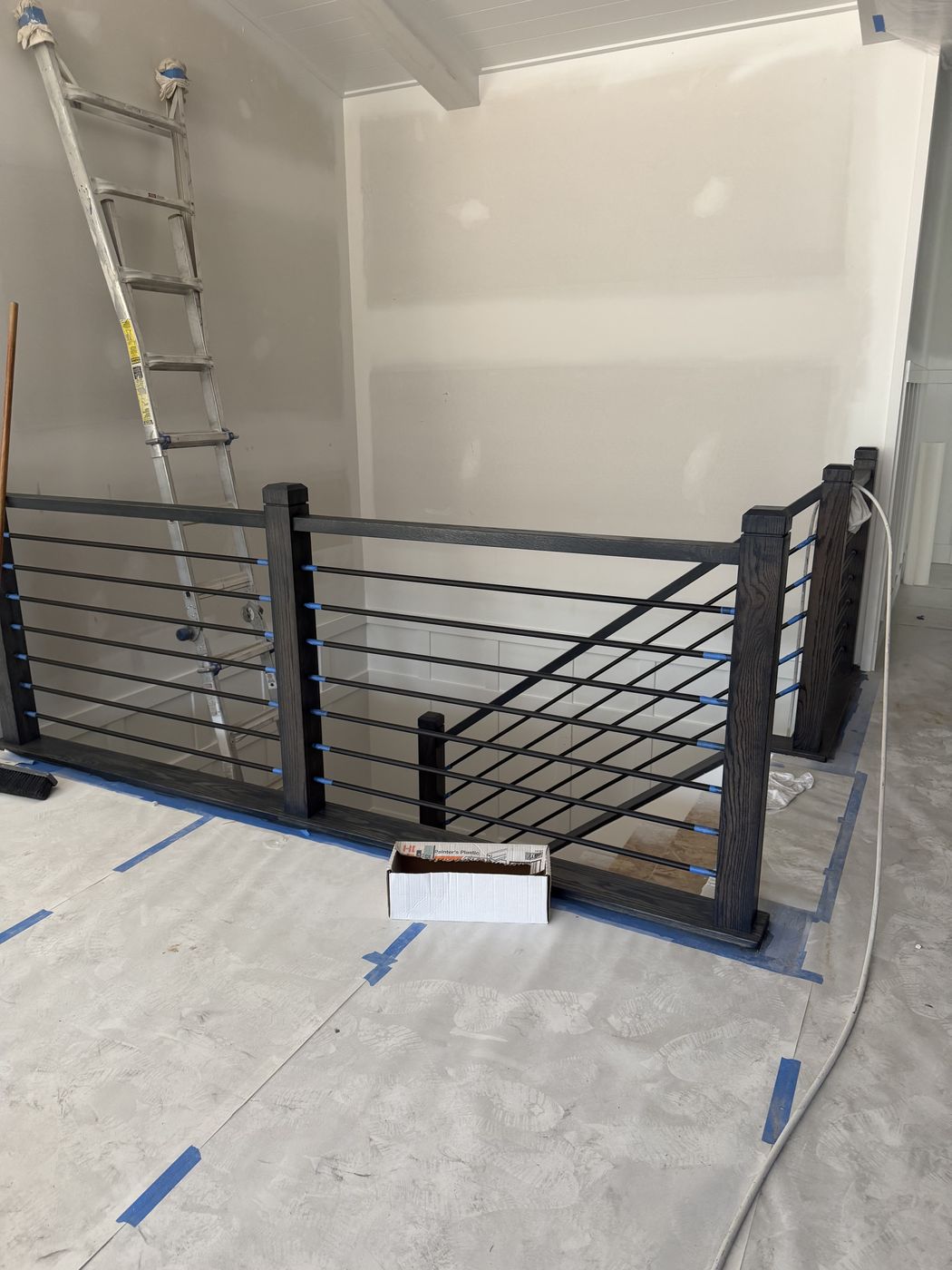 Finished stair rail with floor protection and bare drywall