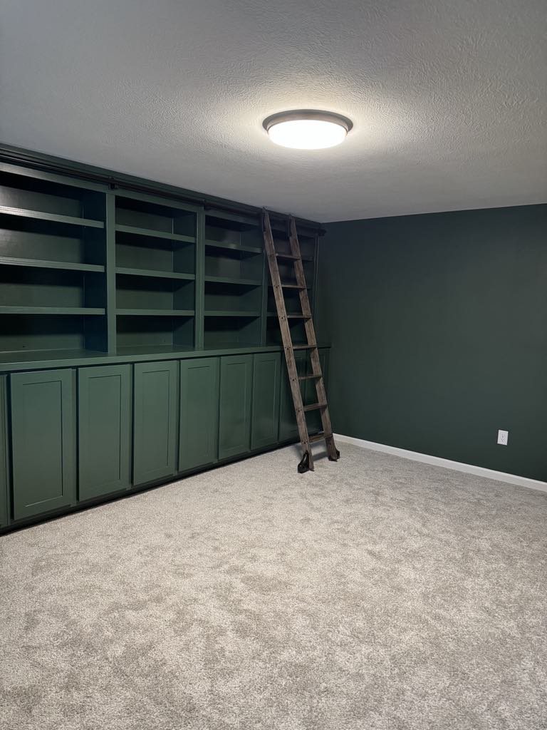 Wide view of green custom library wall and rolling ladder
