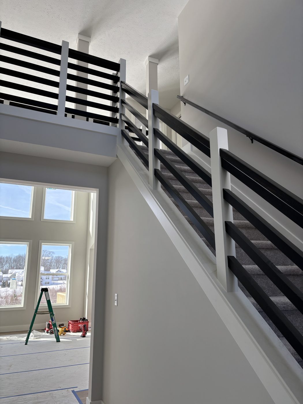 Modern interior stair rail detail with dark railing and metal balusters